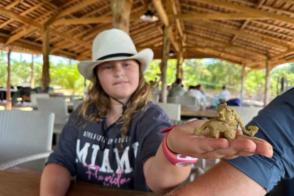 Mi hija sostiene una escultura de barro con forma de elefante que había hecho con barro y semillas.