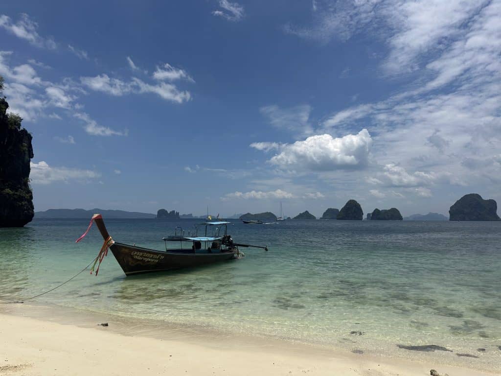 Longtail moored off Hong Island with clear water lapping the white sand shoreline