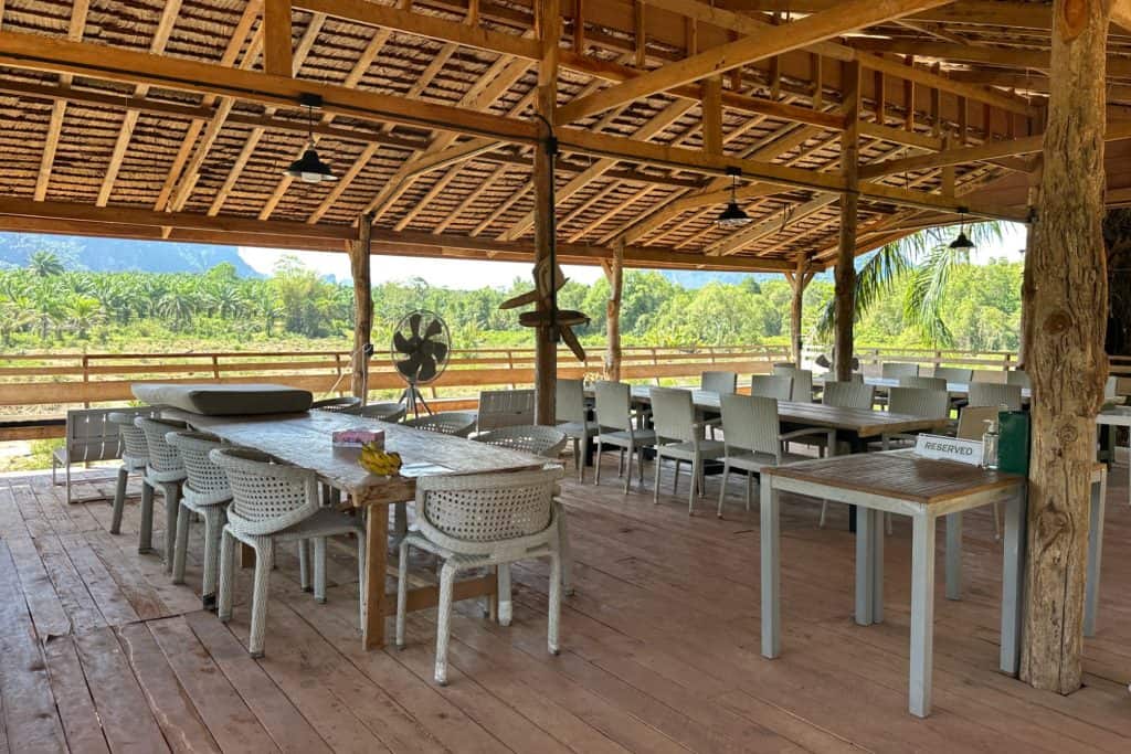 Mesas y sillas vacías en el restaurante de madera con paredes abiertas en el santuario ético de elefantes de los siguientes gigantes en Krabi