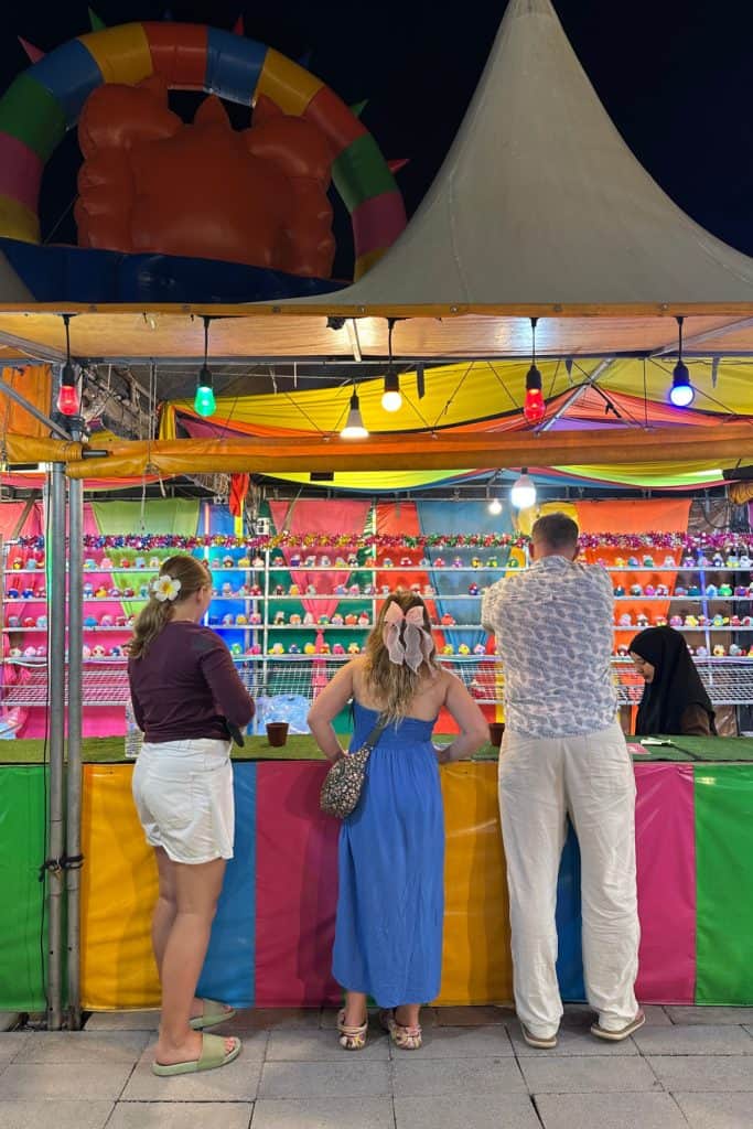 My family stood at a colourful game stall at Ao Nang Landmark Night Market