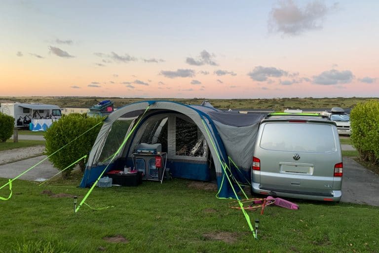 Campervan and awning set up on a campsite in Cornwall as the sun sets