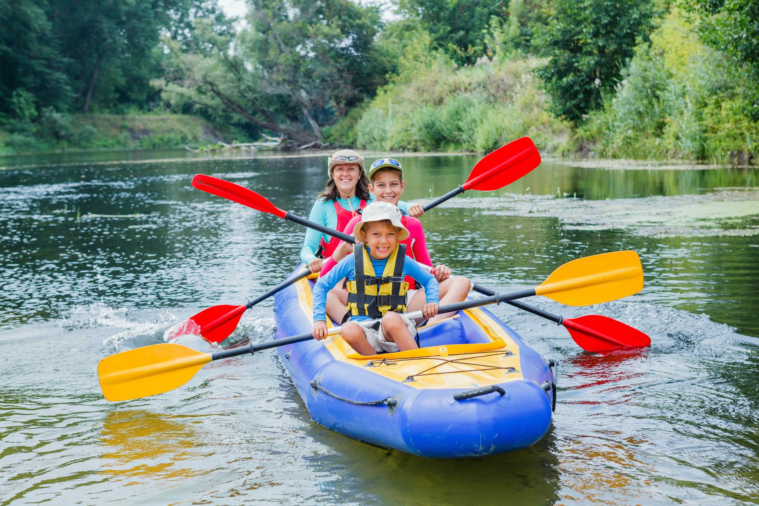 Active happy family. Boy with his sister and mother having fun together enjoying adventurous experience kayaking on the river on a sunny day during summer vacation