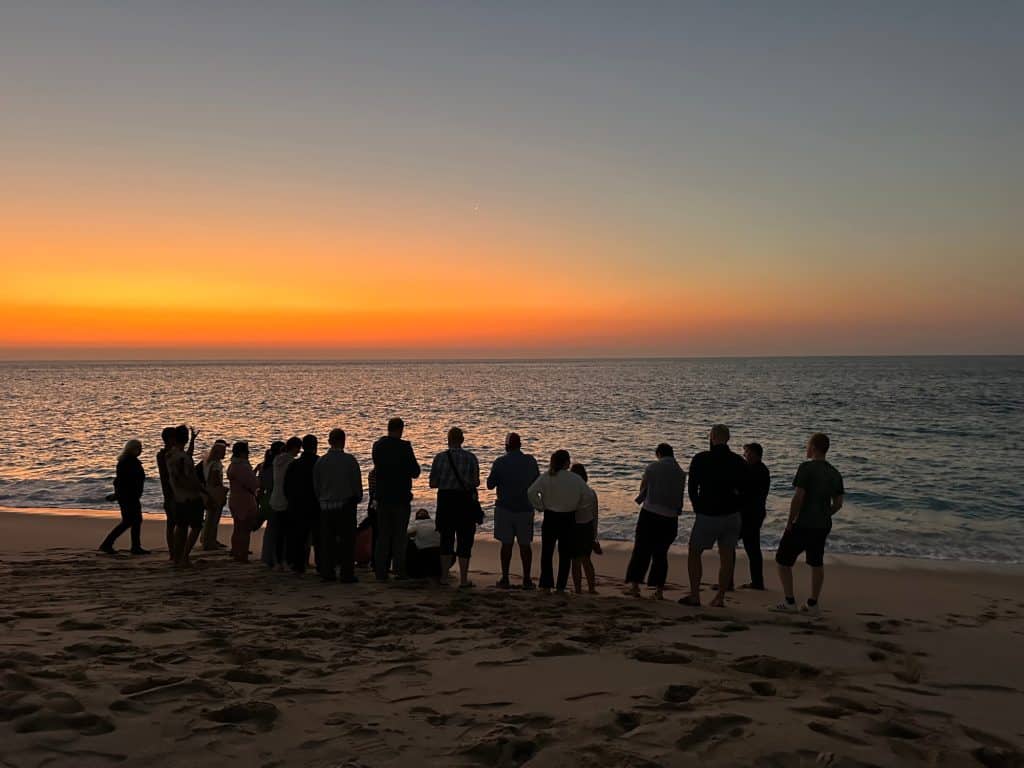 Group of visitors to Ras Al Jinz turtle reserve in Oman on the beach at sun rise