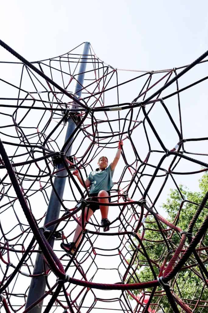 Looking up at my 10-year-old daughter playing on a spiderweb-like climbing frame at Lydiard Park
