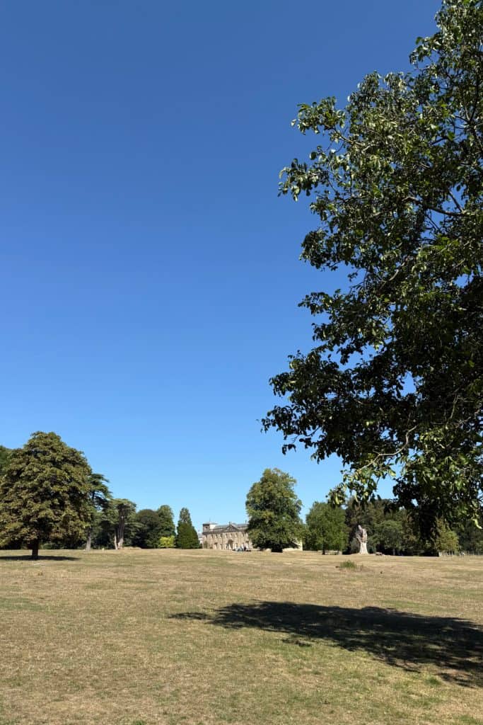 Lydiard Park House, a Georgian stately home made with white stone, seen from across the parkland on a bright sunny day