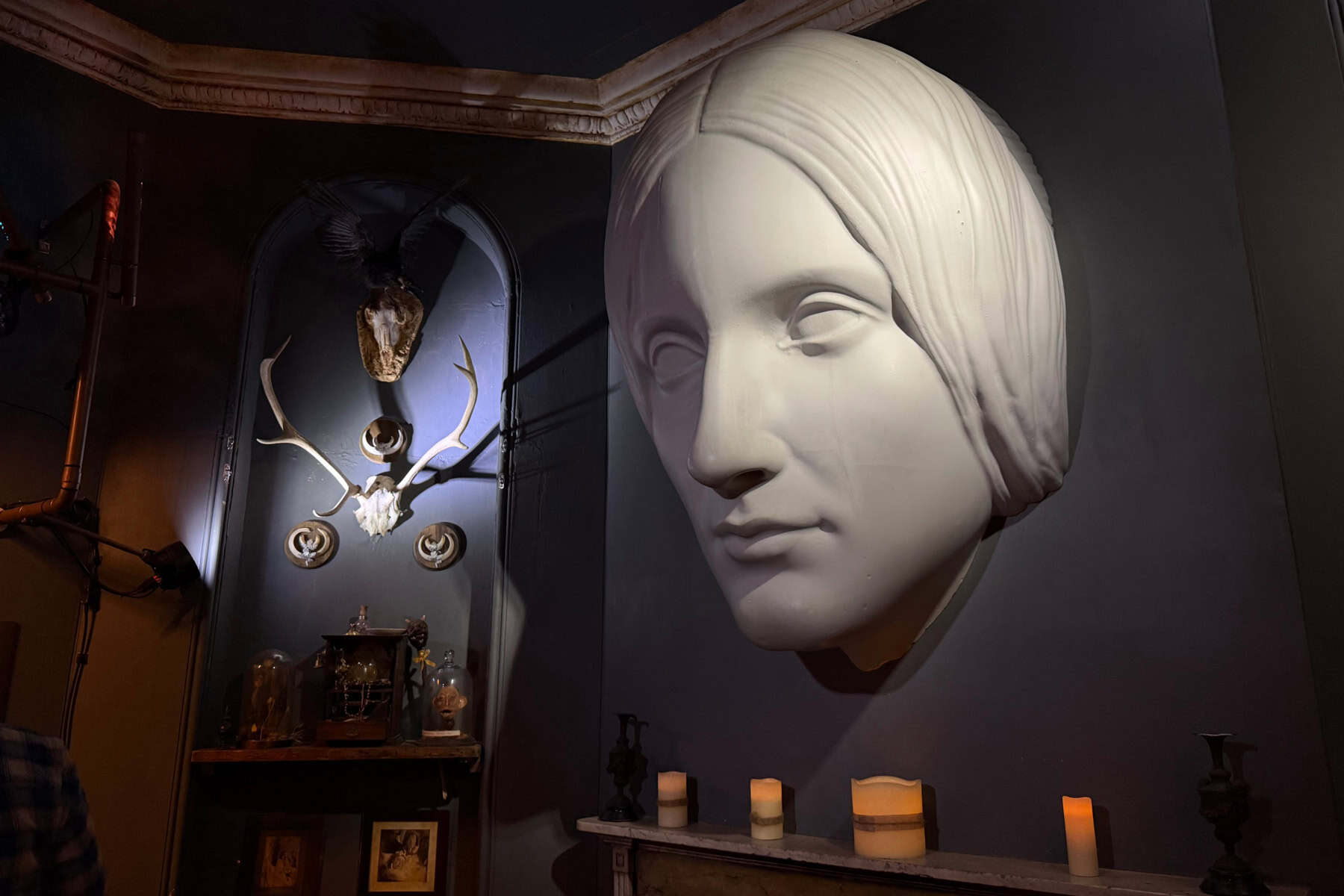 A bust of Mary Shelley above a fireplace in a darkened room of the House of Frankenstein museum