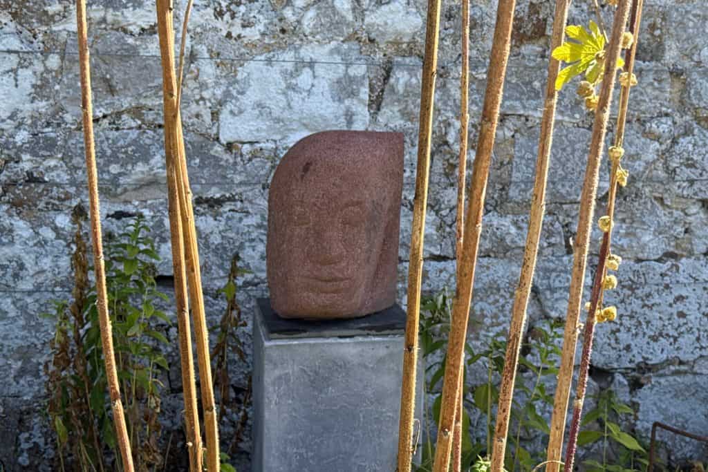 A bronze sculpture of a head in the gardens at Avebury Manor
