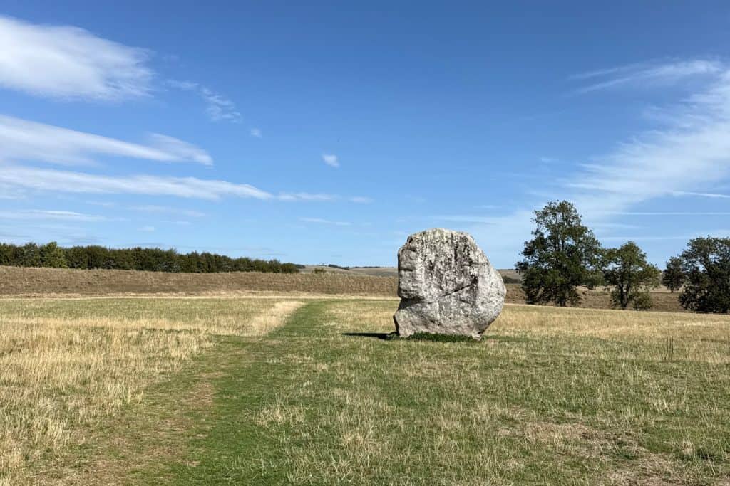 One of the Neolithic stones at Avebury in Wiltshire against a background of rolling green countryside and a blue sky