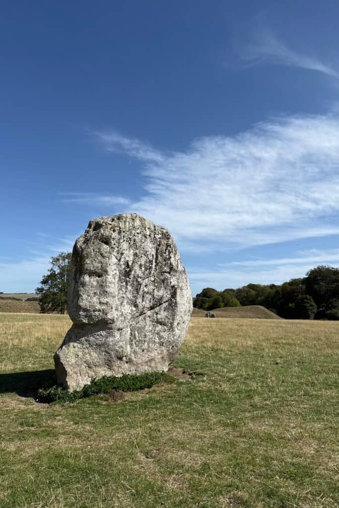 One of the Neolithic stones at Avebury in Wiltshire against a background of rolling green countryside and a blue sky