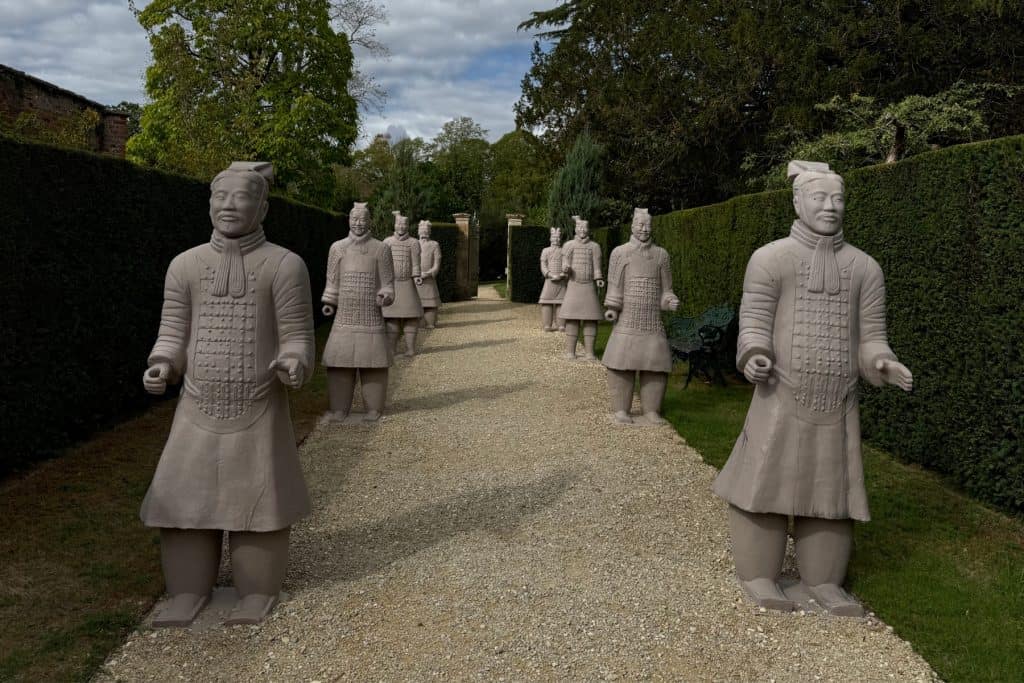 Two rows of Terracotta Warriors between boxed hedges in the Walled Garden of Buscot Estate